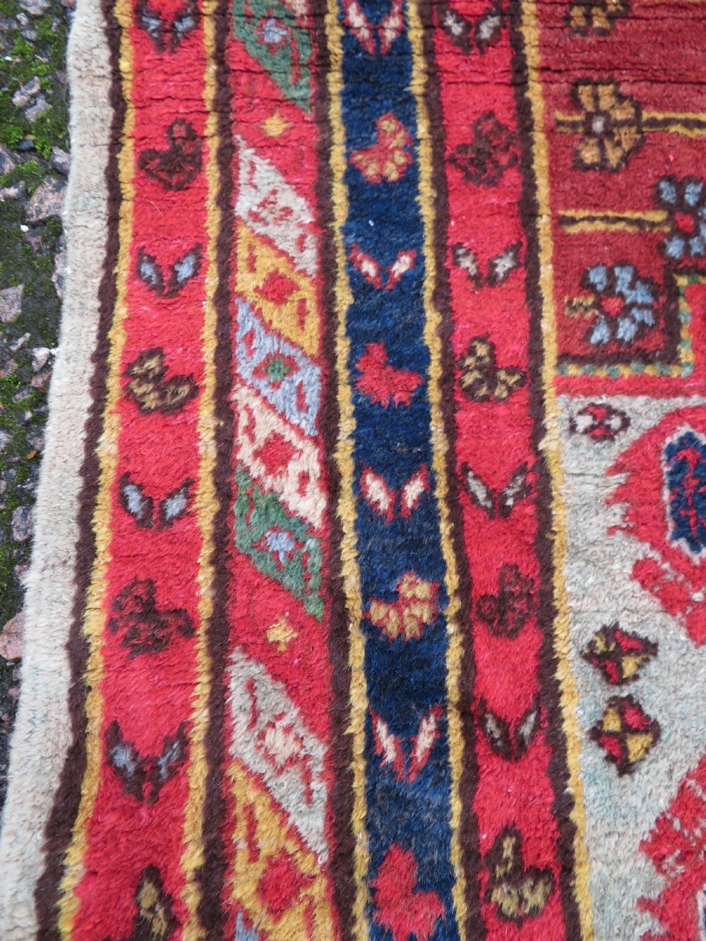 A hand-knotted Turkish village rug featuring central geometric stepped medallions in red, yellow, and navy on a cream field surrounded by decorative borders. View VII
