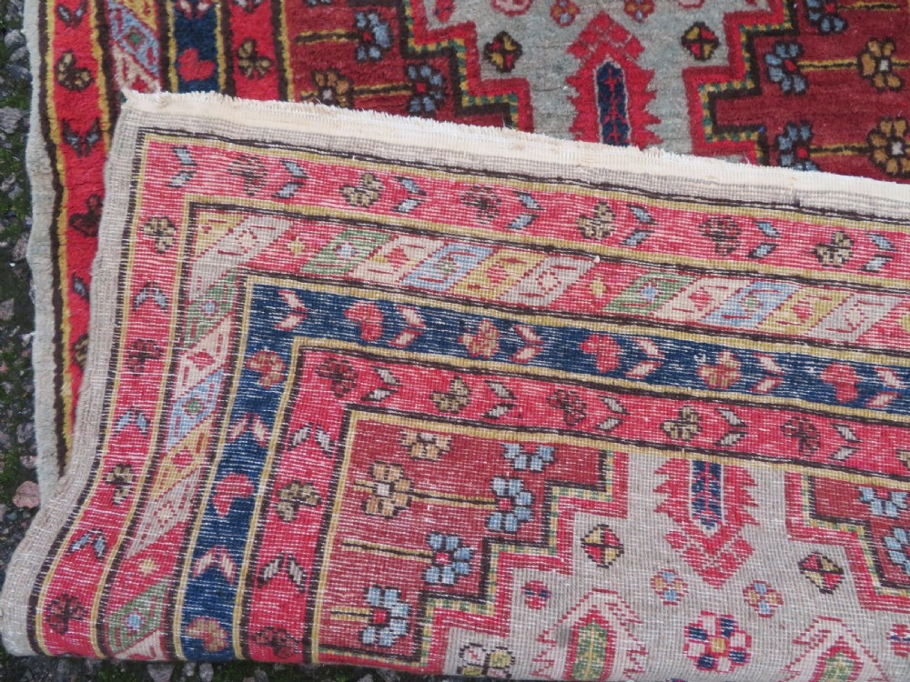 A hand-knotted Turkish village rug featuring central geometric stepped medallions in red, yellow, and navy on a cream field surrounded by decorative borders. View VIII