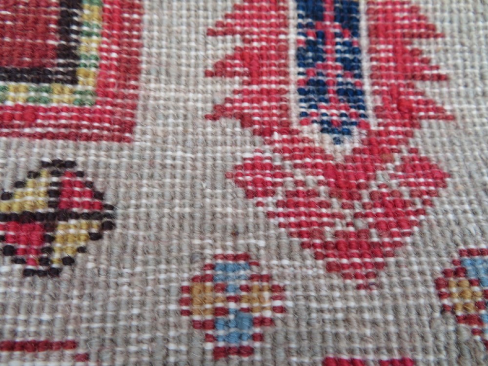 A hand-knotted Turkish village rug featuring central geometric stepped medallions in red, yellow, and navy on a cream field surrounded by decorative borders. View X