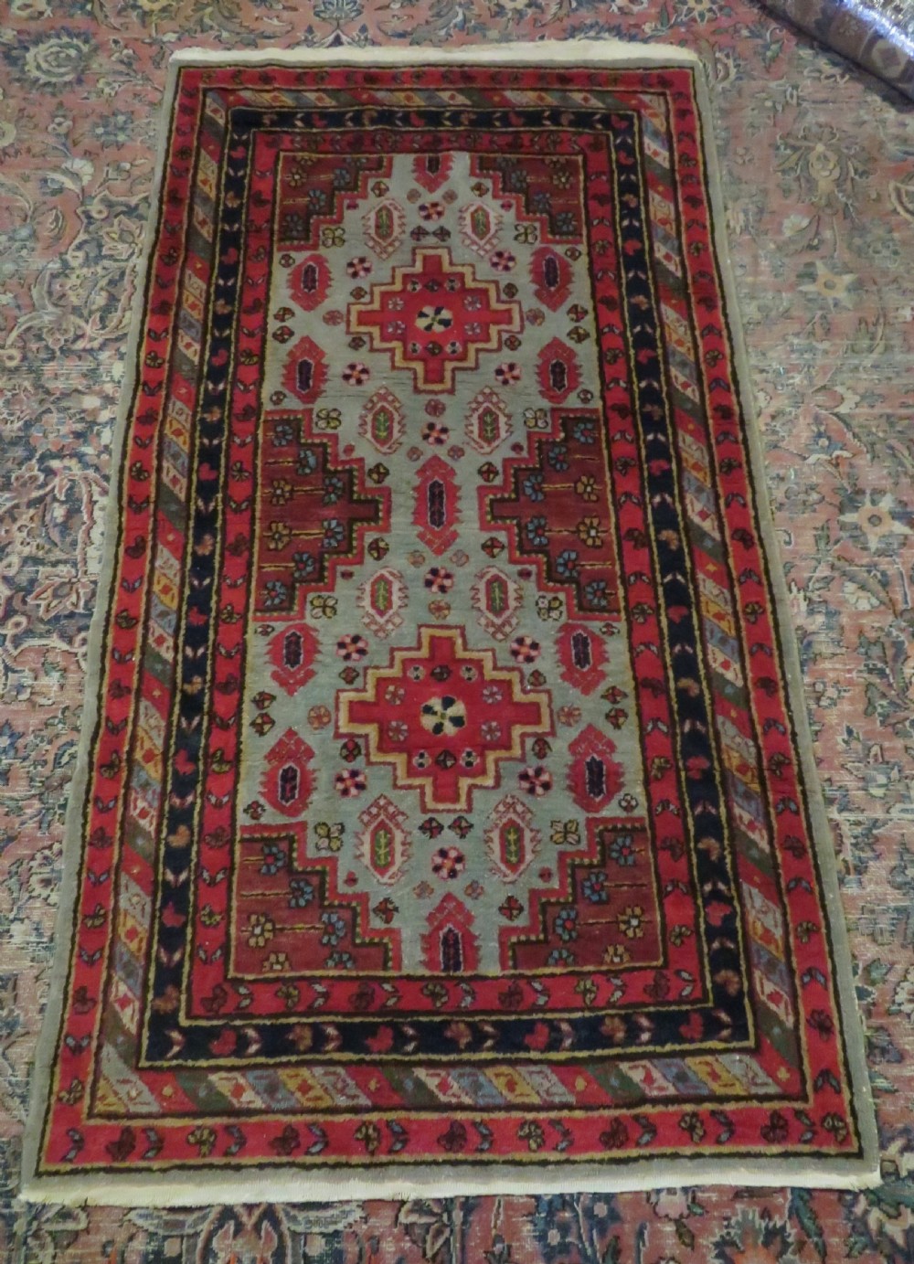 A hand-knotted Turkish village rug featuring central geometric stepped medallions in red, yellow, and navy on a cream field surrounded by decorative borders. View XI