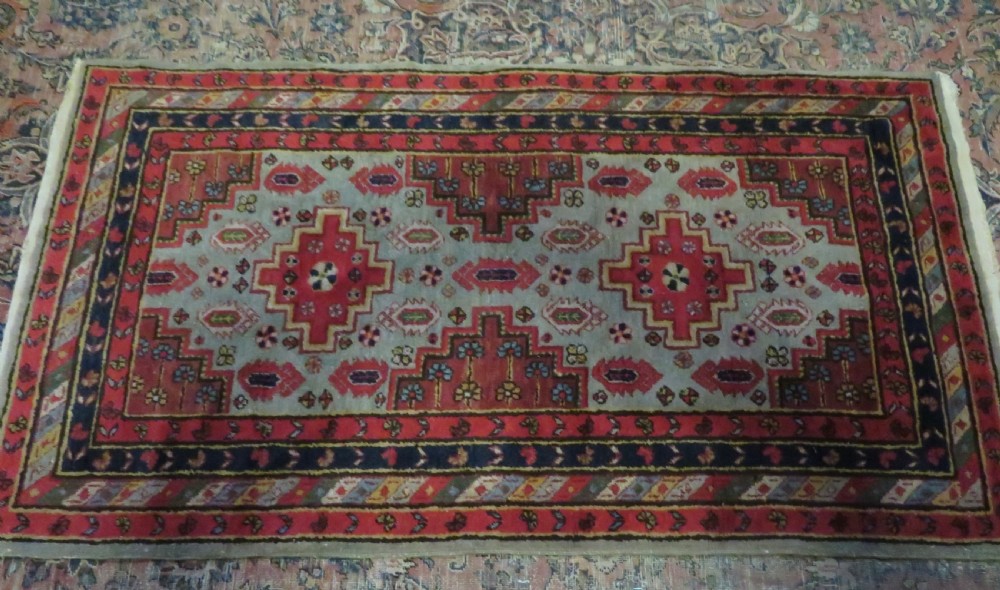 A hand-knotted Turkish village rug featuring central geometric stepped medallions in red, yellow, and navy on a cream field surrounded by decorative borders. View XII