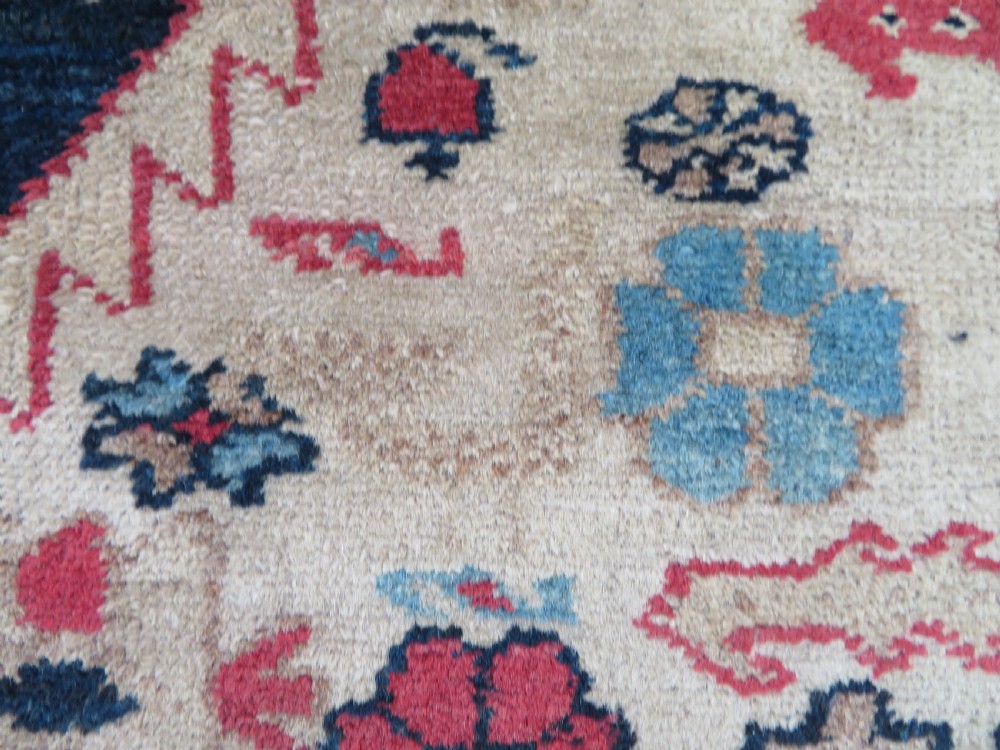 An antique Bakshaish hand-knotted wool rug featuring a navy blue and terracotta central geometric medallion on a cream field with patterned borders. View V