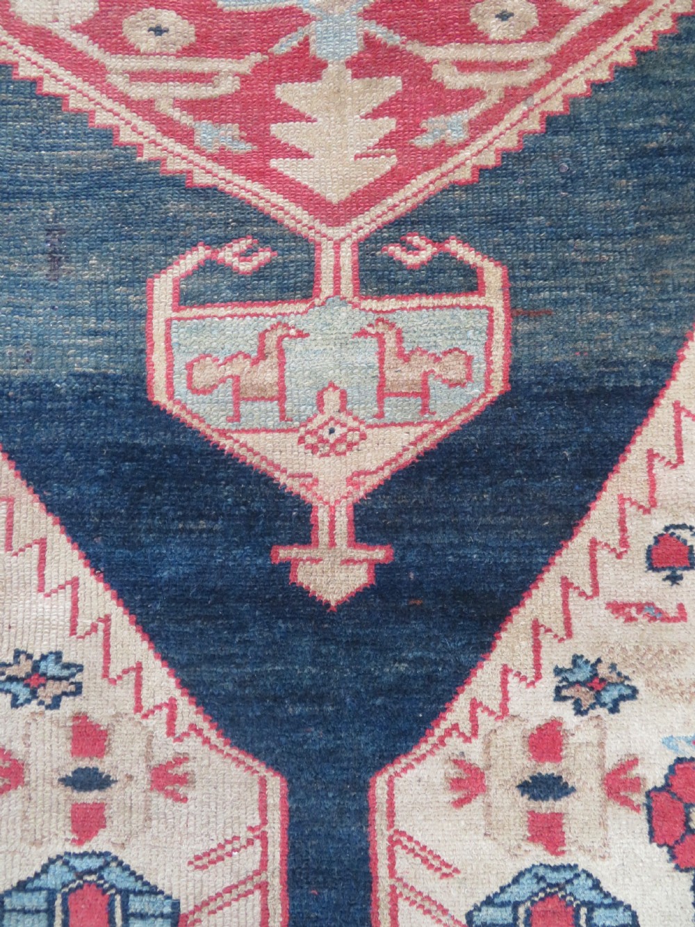 An antique Bakshaish hand-knotted wool rug featuring a navy blue and terracotta central geometric medallion on a cream field with patterned borders. View VI