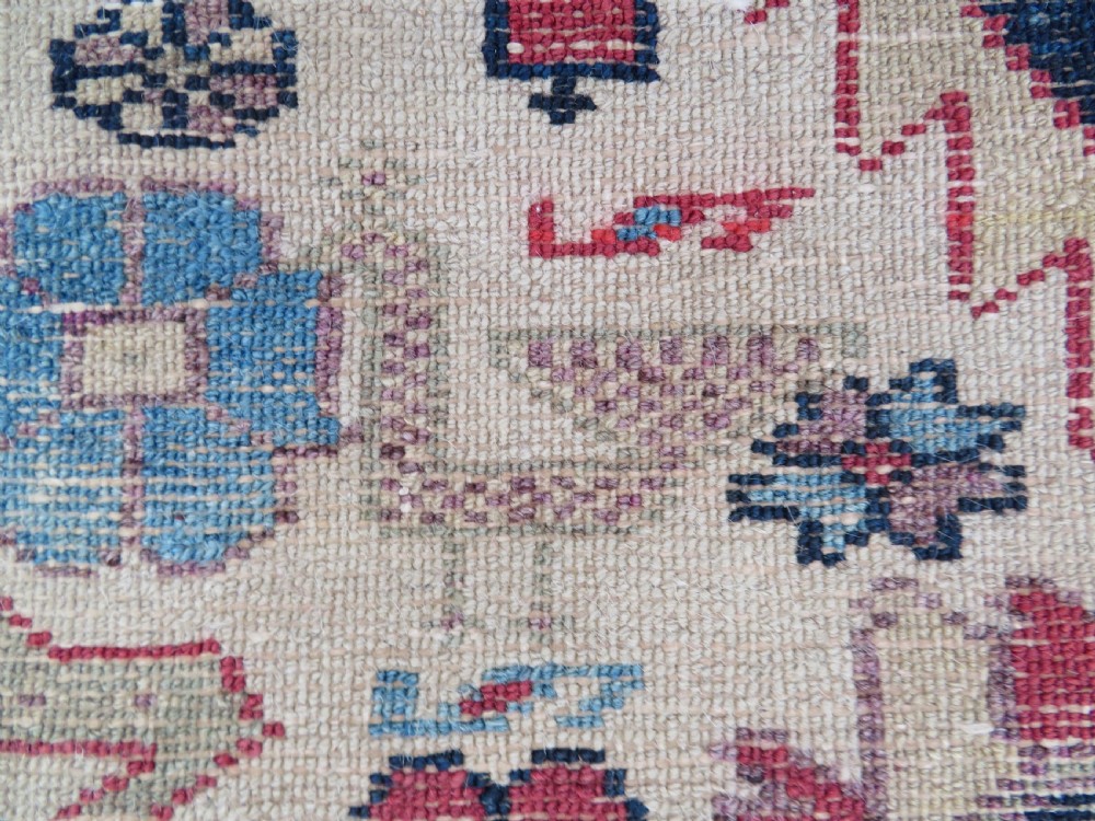 An antique Bakshaish hand-knotted wool rug featuring a navy blue and terracotta central geometric medallion on a cream field with patterned borders. View X