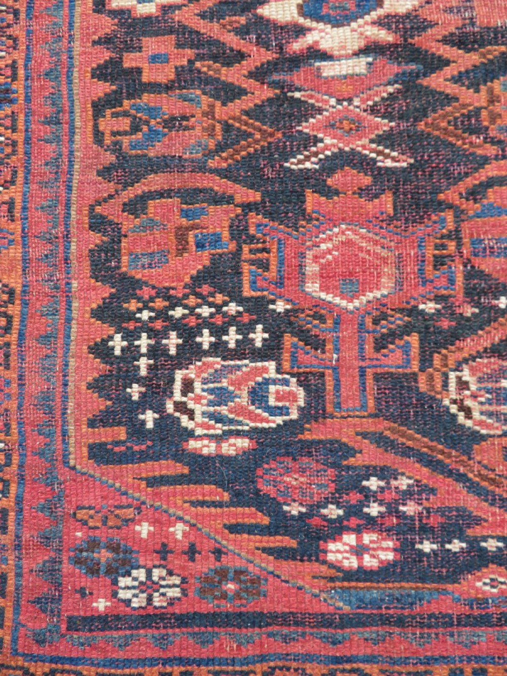 A large hand-knotted Persian Bakhtiari rug featuring geometric diamond medallions on a dark navy field surrounded by a detailed red patterned border. View XII