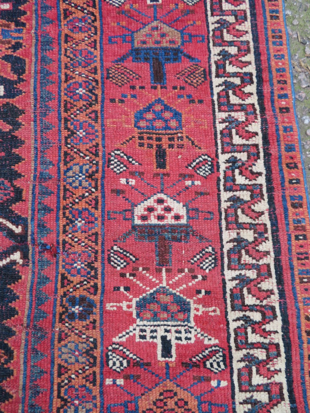 A large hand-knotted Persian Bakhtiari rug featuring geometric diamond medallions on a dark navy field surrounded by a detailed red patterned border. View XIV