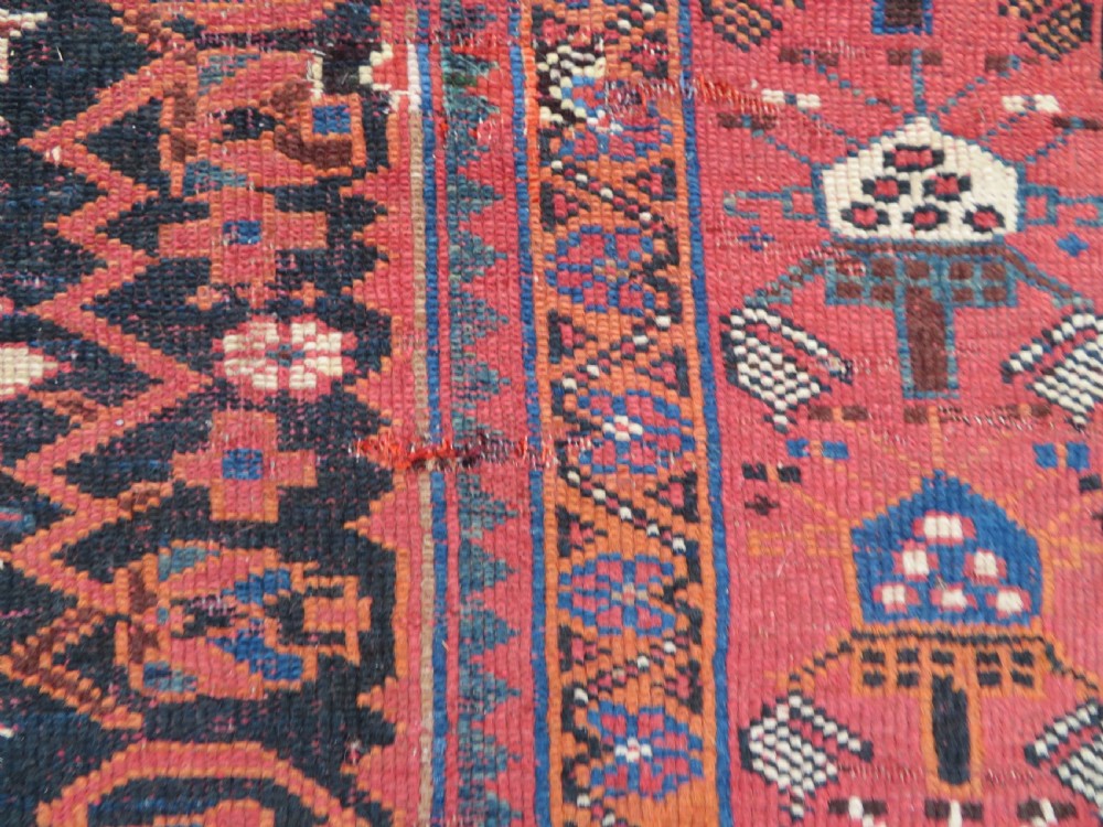 A large hand-knotted Persian Bakhtiari rug featuring geometric diamond medallions on a dark navy field surrounded by a detailed red patterned border. View XVI
