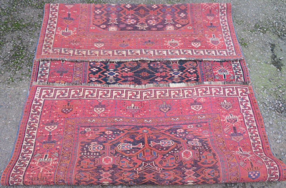 A large hand-knotted Persian Bakhtiari rug featuring geometric diamond medallions on a dark navy field surrounded by a detailed red patterned border. View XVIII