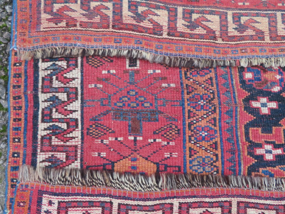 A large hand-knotted Persian Bakhtiari rug featuring geometric diamond medallions on a dark navy field surrounded by a detailed red patterned border. View XIX