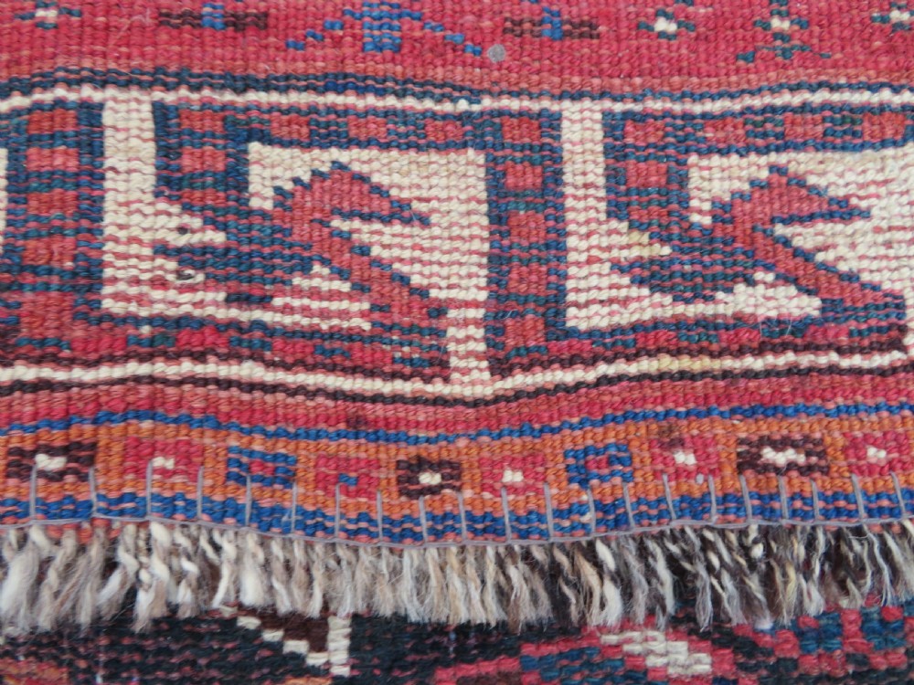 A large hand-knotted Persian Bakhtiari rug featuring geometric diamond medallions on a dark navy field surrounded by a detailed red patterned border. View XXI