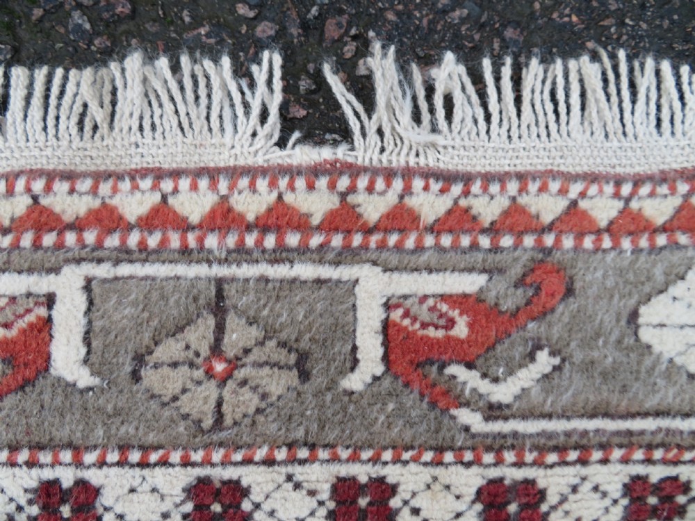 A hand-knotted antique Turkish Melas wool carpet featuring a terracotta red geometric diamond medallion on an ivory field with complex geometric borders. View VII