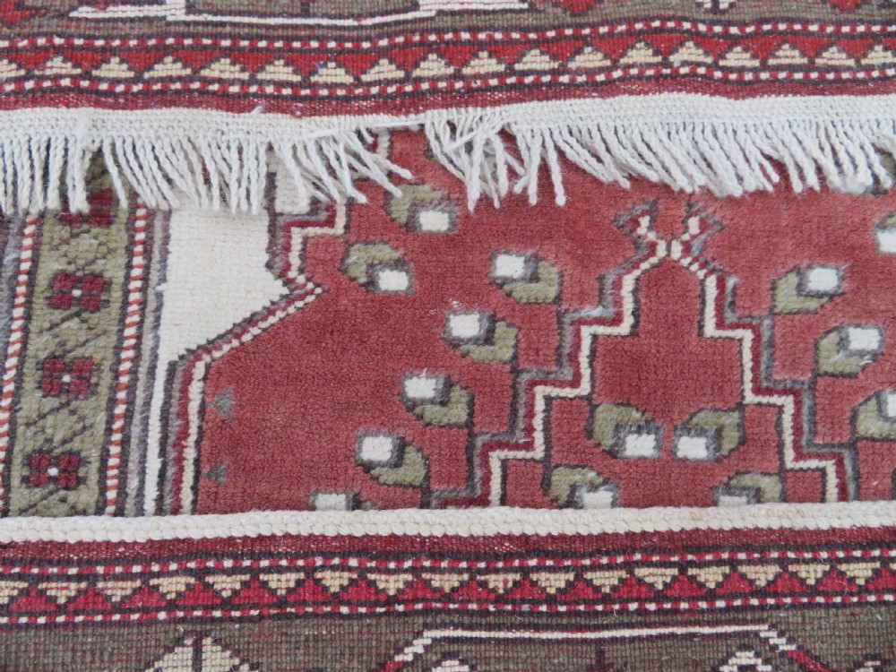 A hand-knotted antique Turkish Melas wool carpet featuring a terracotta red geometric diamond medallion on an ivory field with complex geometric borders. View XII