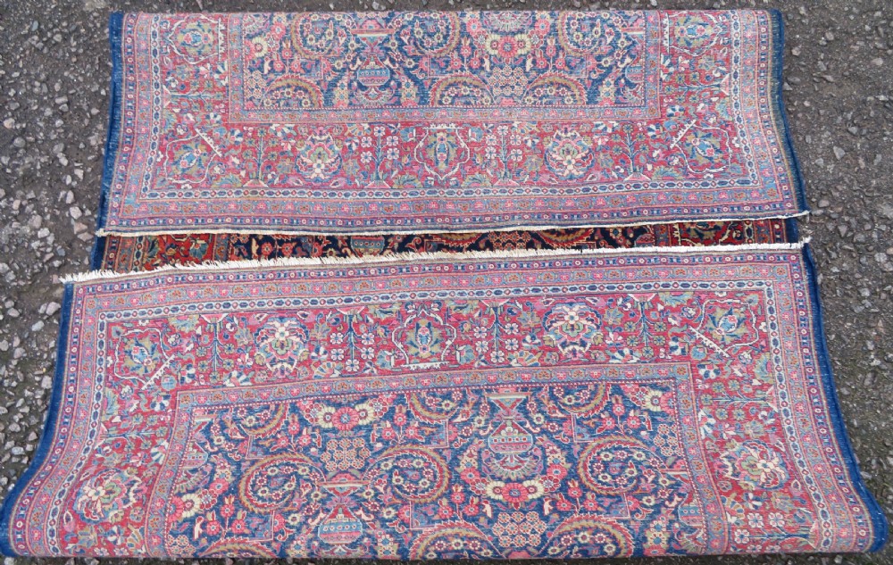 An antique hand-knotted Persian Kashan rug featuring an intricate blue central field with repeating floral urn motifs surrounded by a detailed red multi-banded border. View XIII