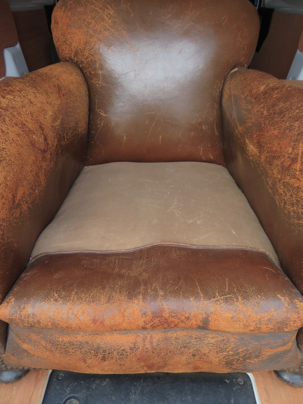 A distressed brown leather Art Deco club armchair with brass stud trimming along the rolled arms and a velvet seat cushion. View II