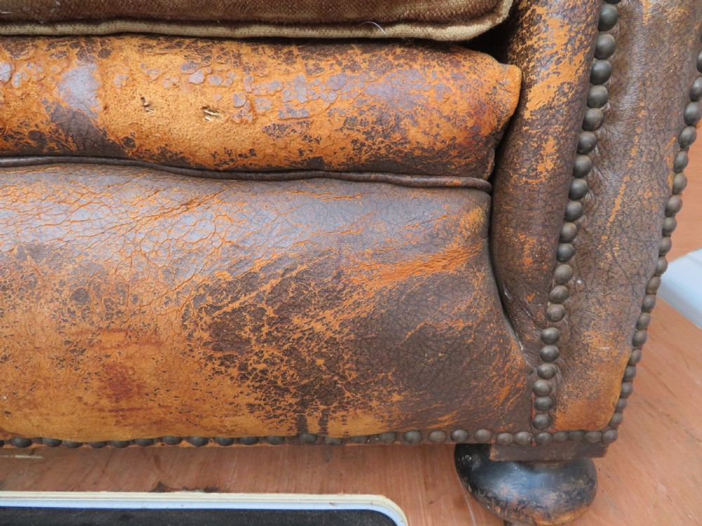 A distressed brown leather Art Deco club armchair with brass stud trimming along the rolled arms and a velvet seat cushion. View III