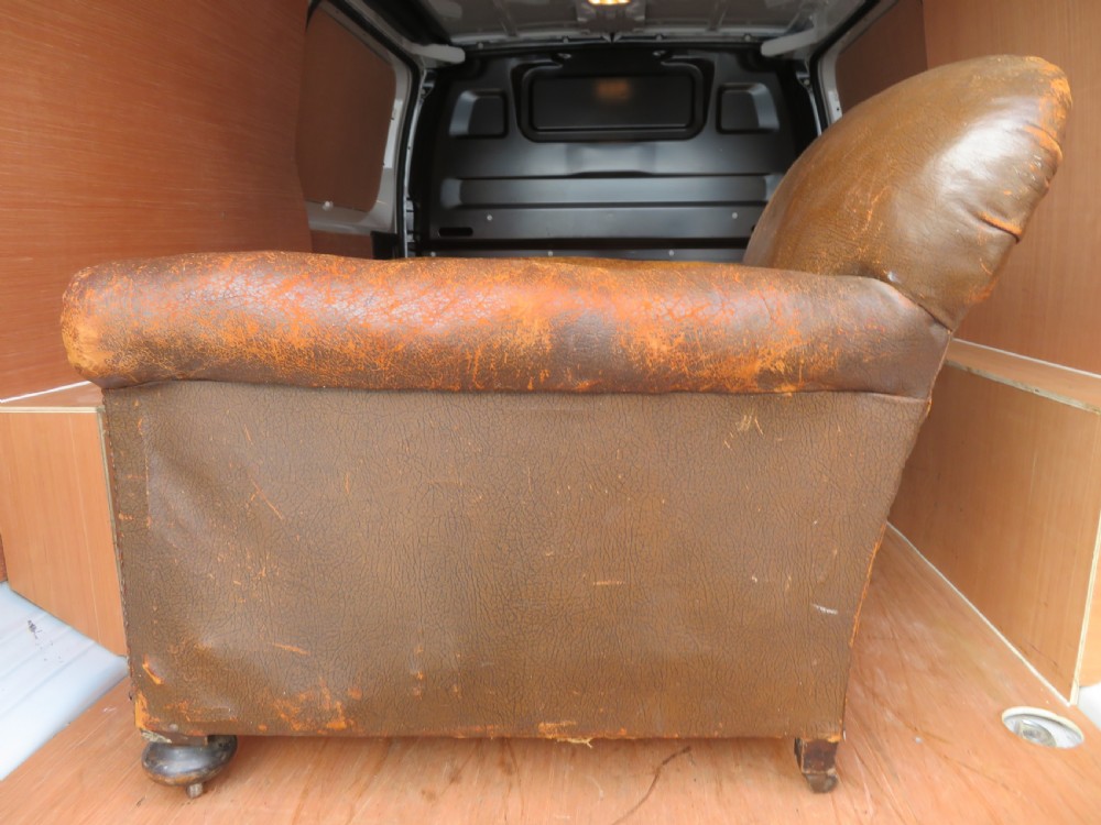A distressed brown leather Art Deco club armchair with brass stud trimming along the rolled arms and a velvet seat cushion. View VI