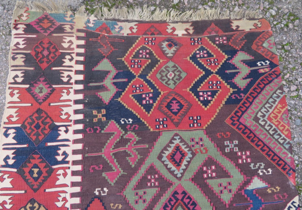 A long handwoven Turkish flatweave Kilim runner featuring intricate geometric diamond medallions in red, navy blue, green, and cream. View II