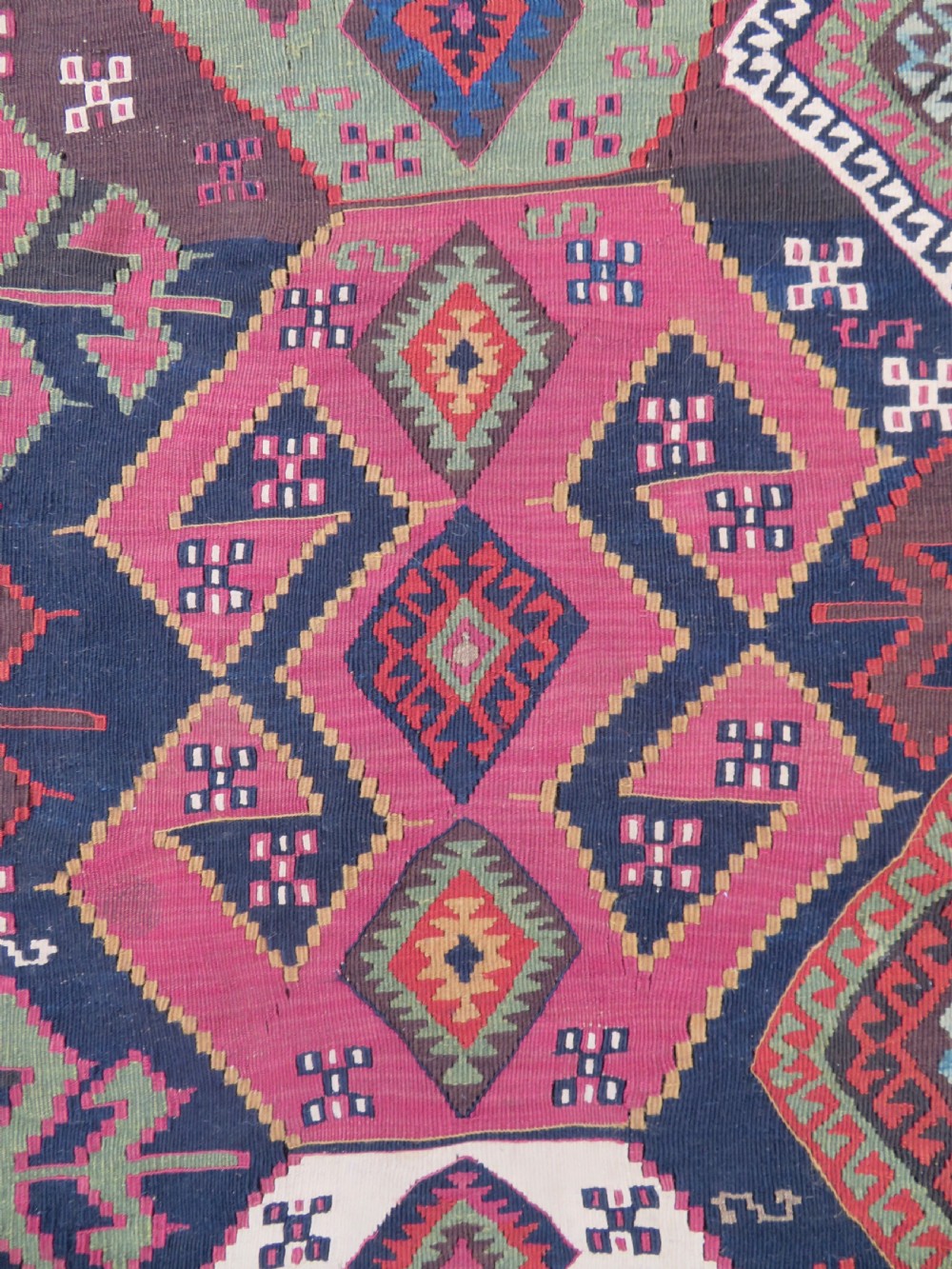 A long handwoven Turkish flatweave Kilim runner featuring intricate geometric diamond medallions in red, navy blue, green, and cream. View III