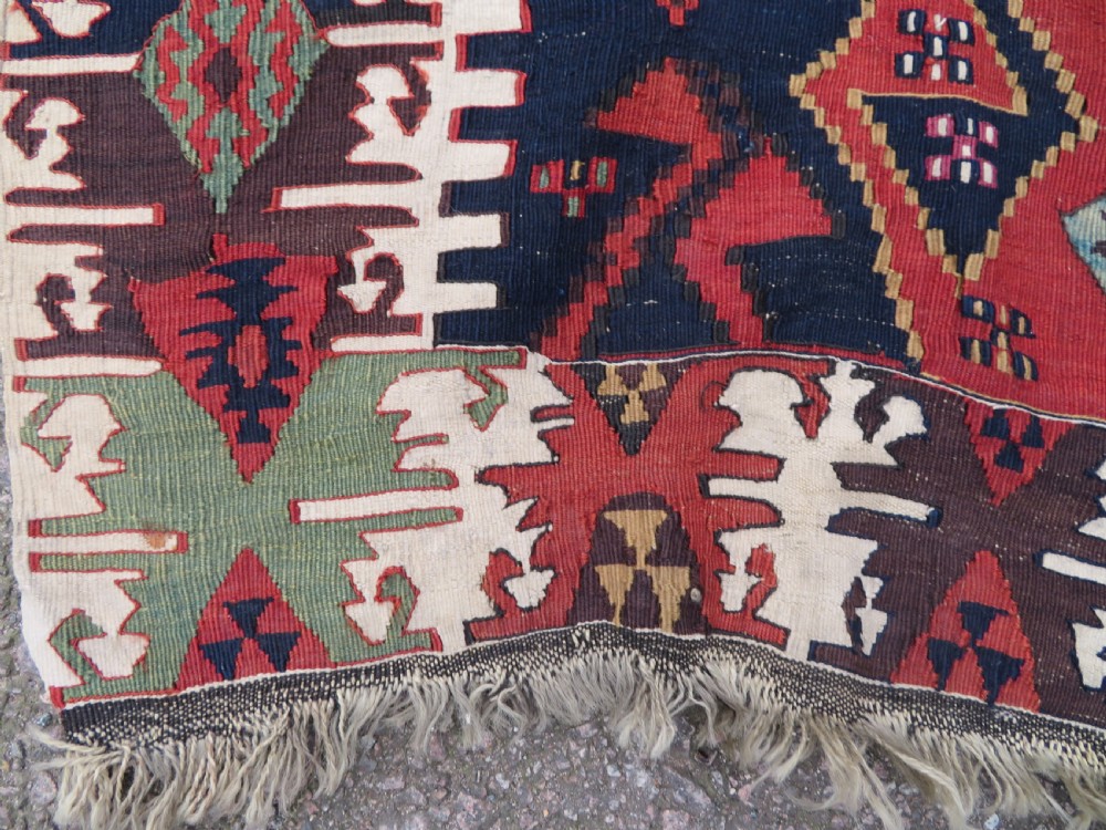 A long handwoven Turkish flatweave Kilim runner featuring intricate geometric diamond medallions in red, navy blue, green, and cream. View VI