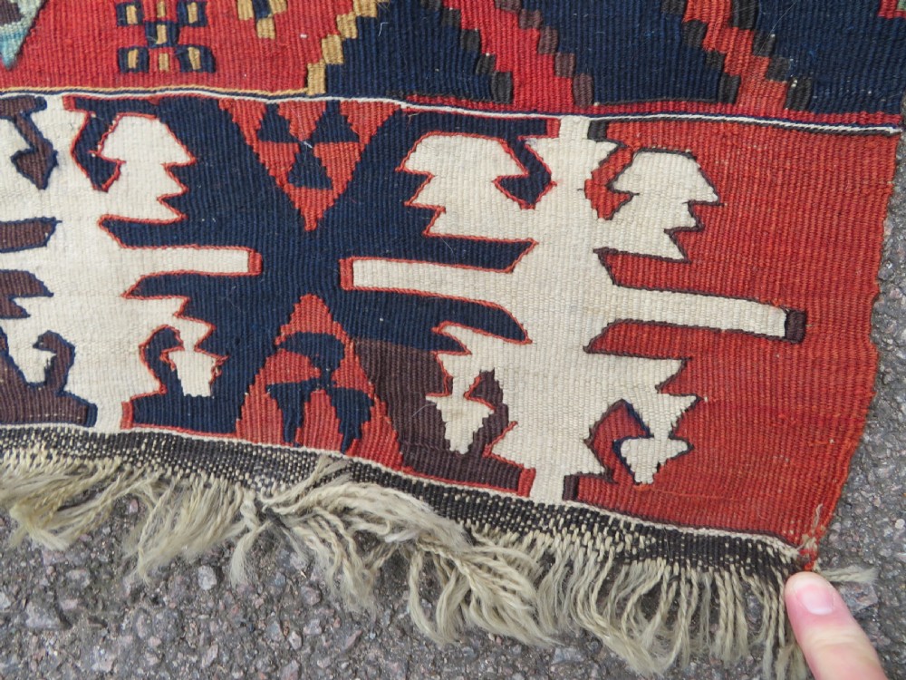 A long handwoven Turkish flatweave Kilim runner featuring intricate geometric diamond medallions in red, navy blue, green, and cream. View VII
