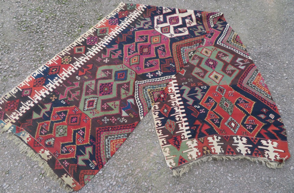 A long handwoven Turkish flatweave Kilim runner featuring intricate geometric diamond medallions in red, navy blue, green, and cream. View X