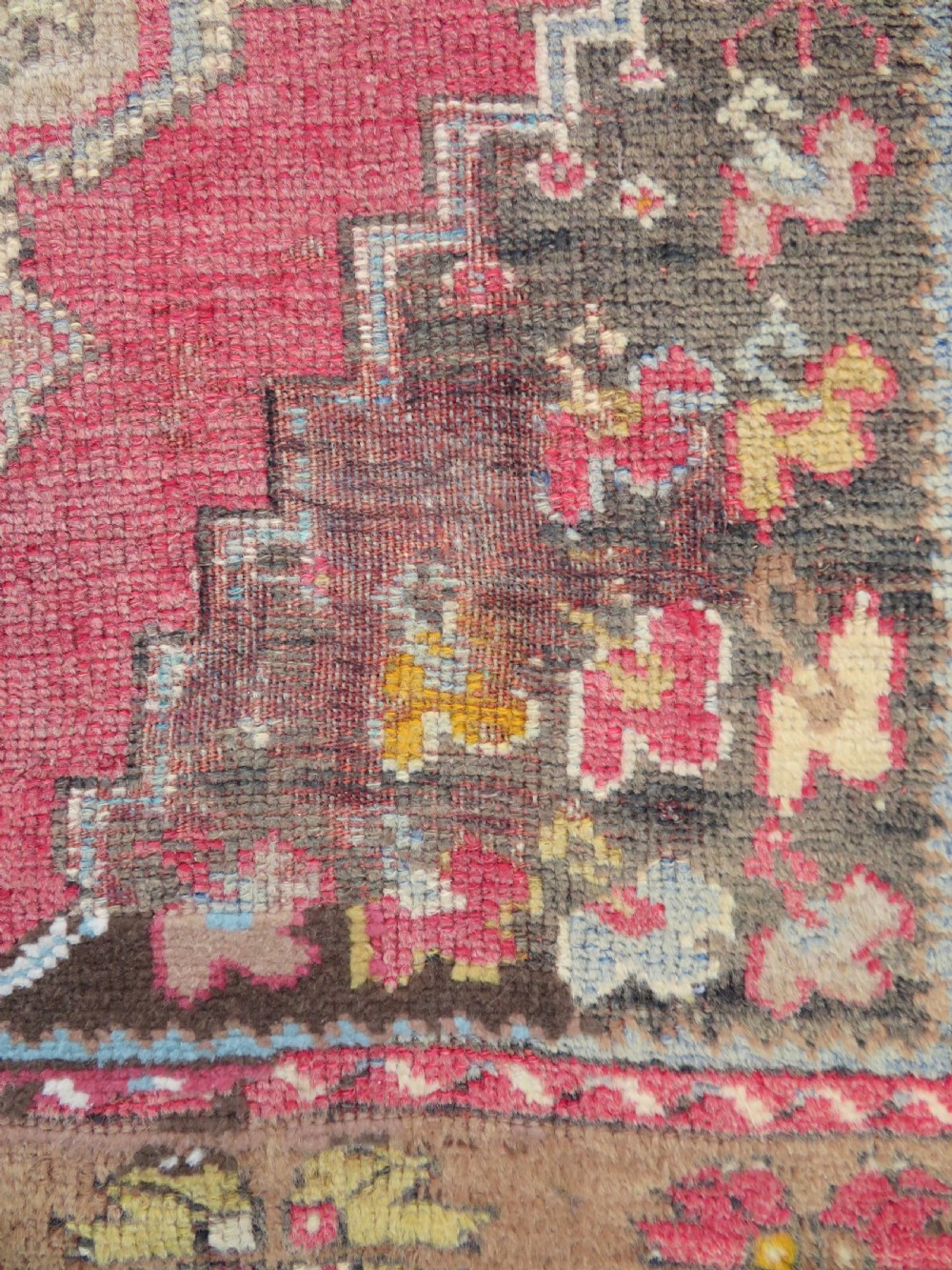 An antique hand-knotted Turkish Mujur wool rug featuring a stepped central medallion on a red field with patterned borders and fringed edges. View VII