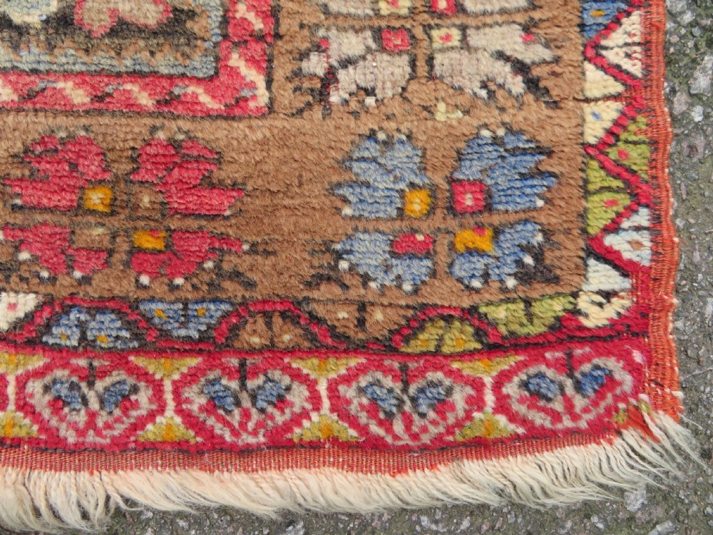 An antique hand-knotted Turkish Mujur wool rug featuring a stepped central medallion on a red field with patterned borders and fringed edges. View VIII