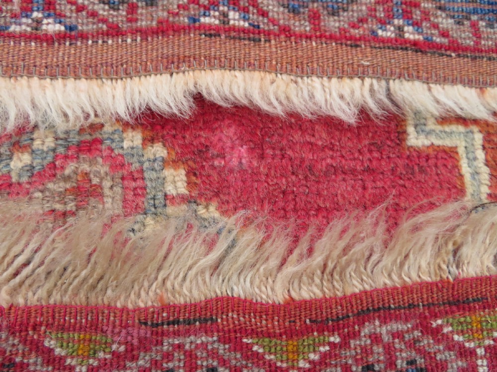 An antique hand-knotted Turkish Mujur wool rug featuring a stepped central medallion on a red field with patterned borders and fringed edges. View XI