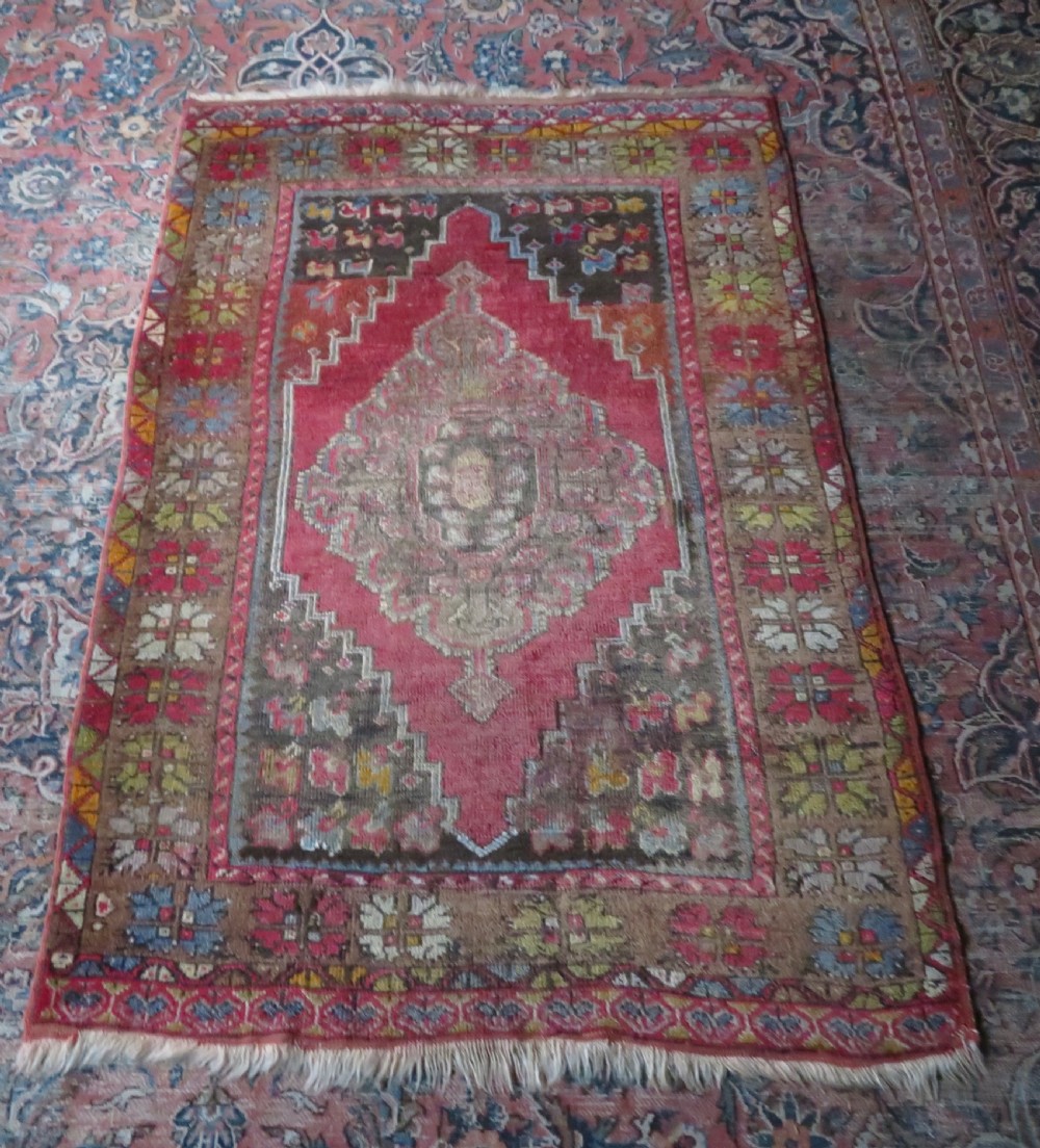 An antique hand-knotted Turkish Mujur wool rug featuring a stepped central medallion on a red field with patterned borders and fringed edges. View XIII