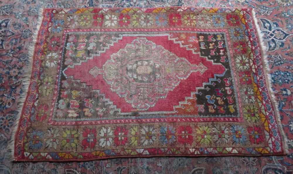 An antique hand-knotted Turkish Mujur wool rug featuring a stepped central medallion on a red field with patterned borders and fringed edges. View XIV