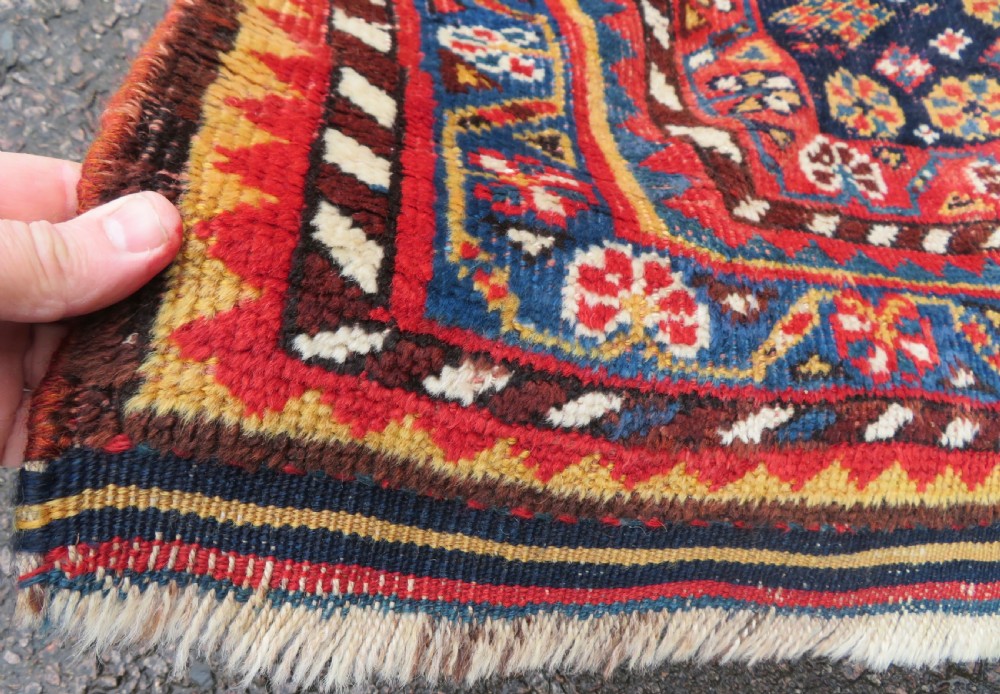 An antique hand-knotted wool kelleh rug featuring a central tree of life motif in red, yellow, and light blue against a dark navy field. View VI