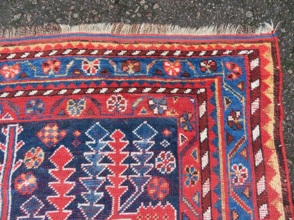 An antique hand-knotted wool kelleh rug featuring a central tree of life motif in red, yellow, and light blue against a dark navy field. View VIII