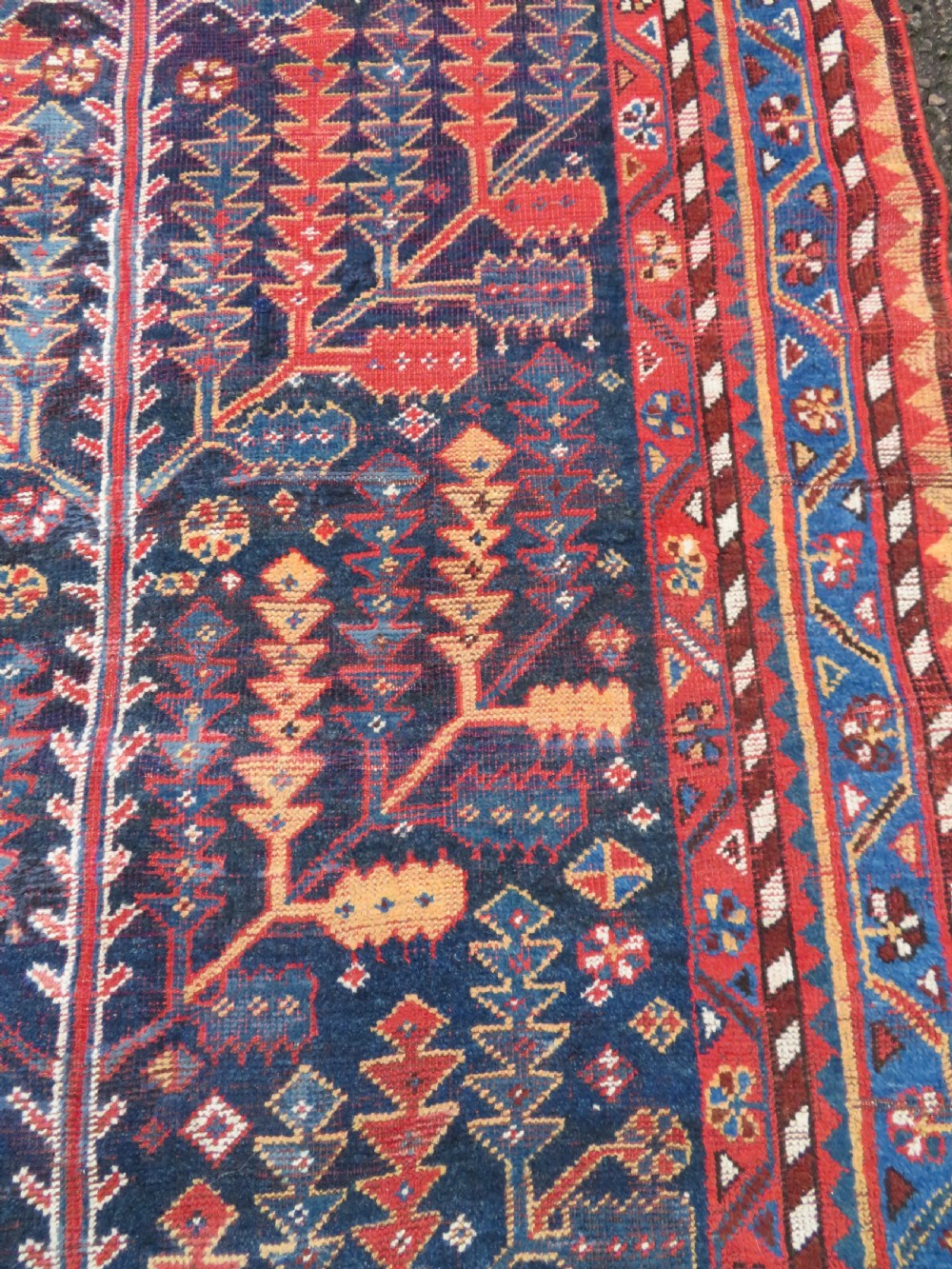 An antique hand-knotted wool kelleh rug featuring a central tree of life motif in red, yellow, and light blue against a dark navy field. View XI