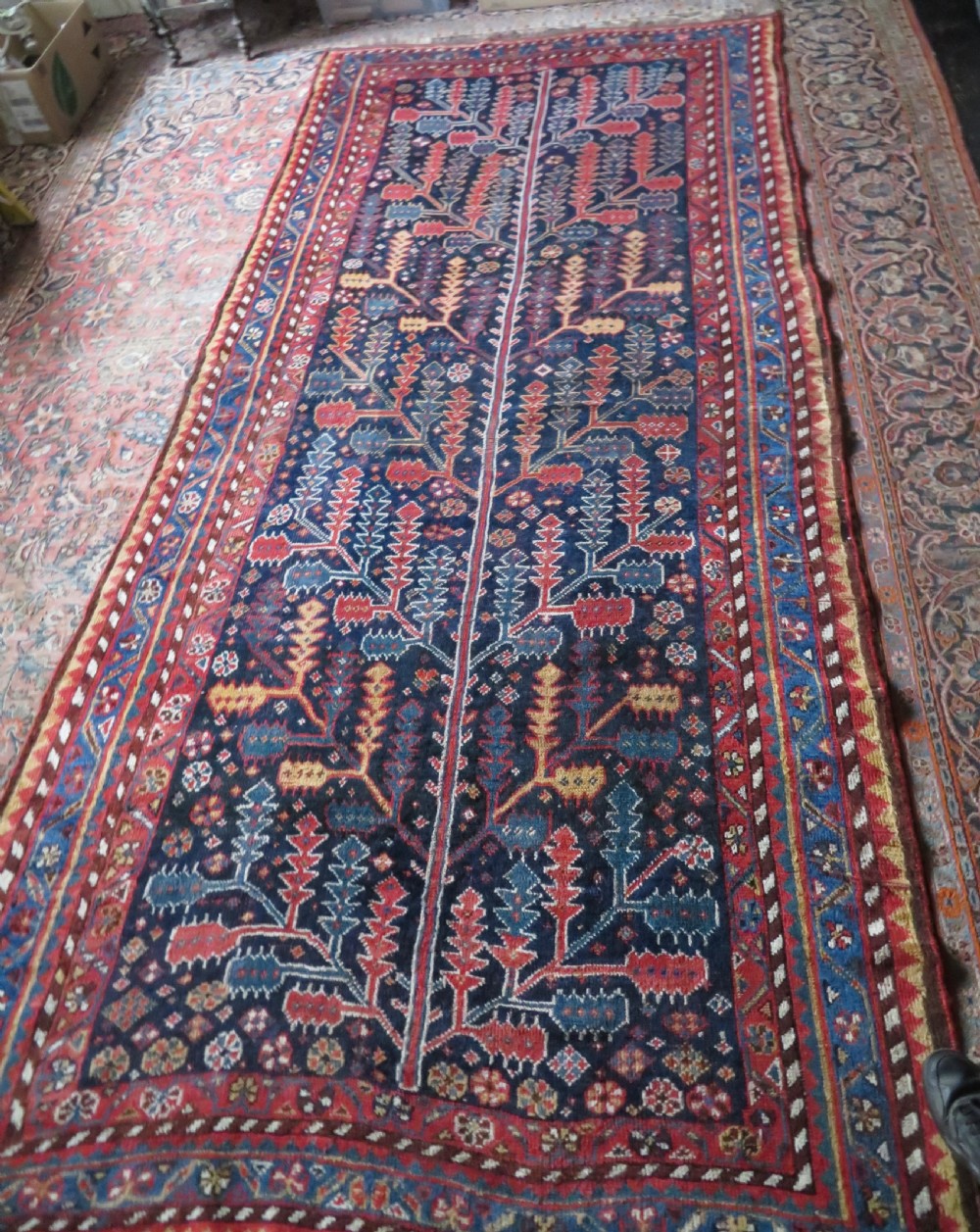 An antique hand-knotted wool kelleh rug featuring a central tree of life motif in red, yellow, and light blue against a dark navy field. View XXII