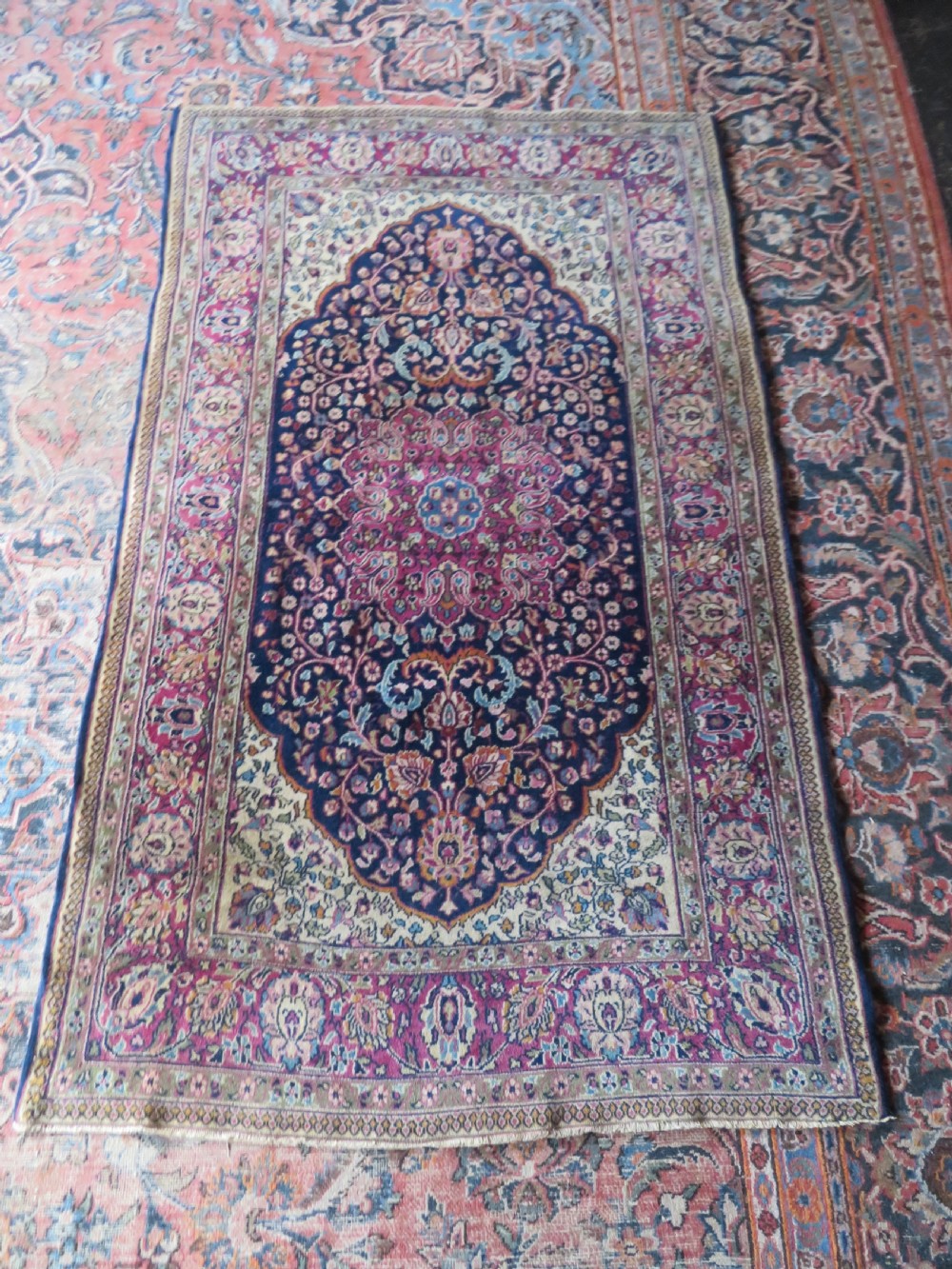 A rectangular hand-knotted wool rug featuring a central indigo floral medallion, cream spandrels, and a magenta border. View XIII