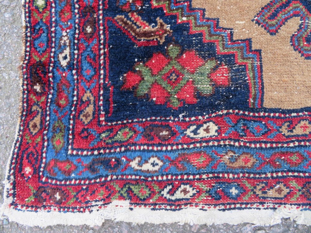 An antique hand-knotted Persian Hamadan wool rug featuring a geometric central medallion on a camel field with navy and red accents. View VIII