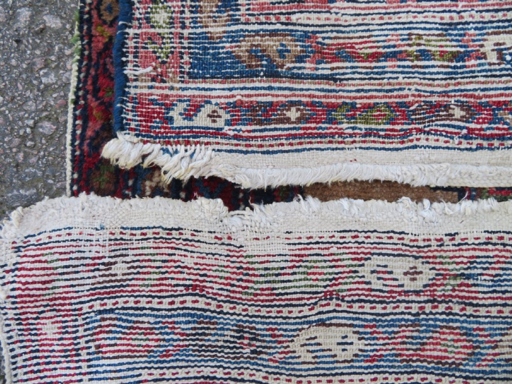 An antique hand-knotted Persian Hamadan wool rug featuring a geometric central medallion on a camel field with navy and red accents. View XII