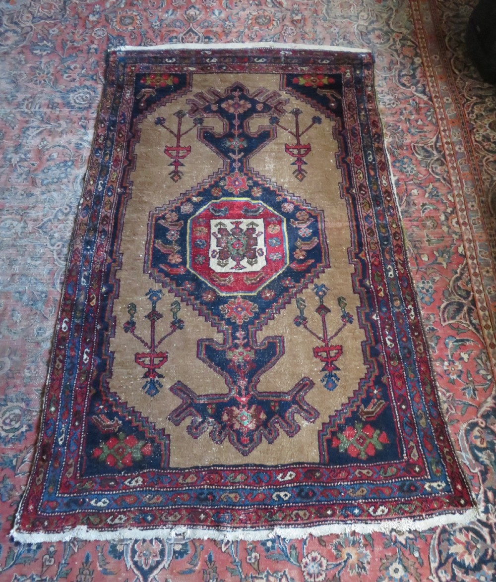 An antique hand-knotted Persian Hamadan wool rug featuring a geometric central medallion on a camel field with navy and red accents. View XVII