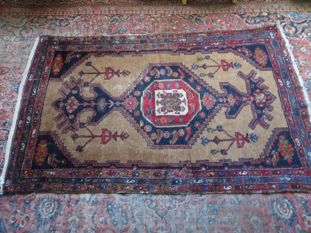An antique hand-knotted Persian Hamadan wool rug featuring a geometric central medallion on a camel field with navy and red accents. View XVIII