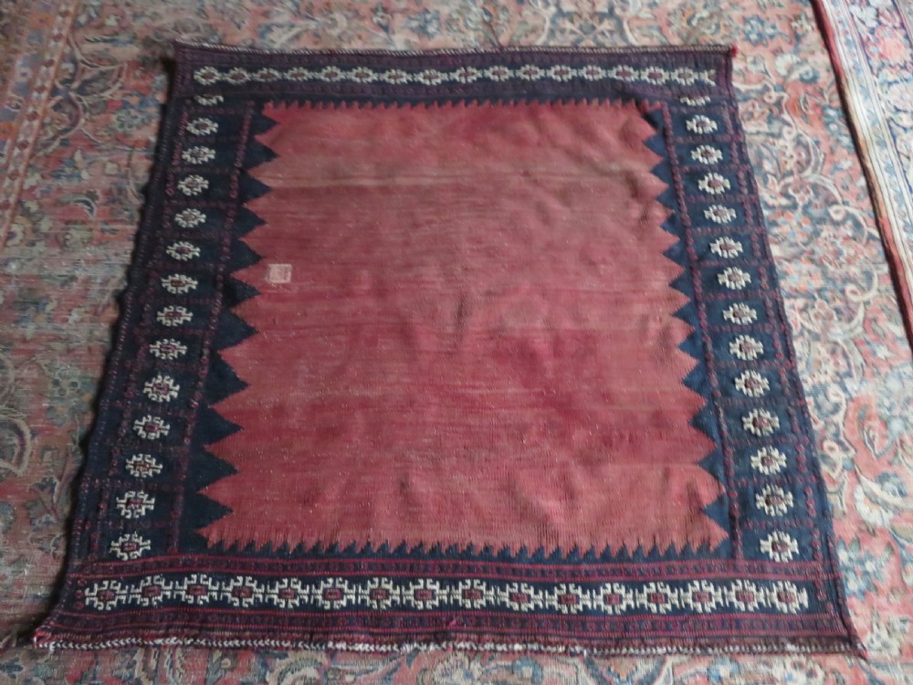 A square antique Afshar flatweave sofreh rug with a faded red central field and serrated indigo blue geometric borders. View XI
