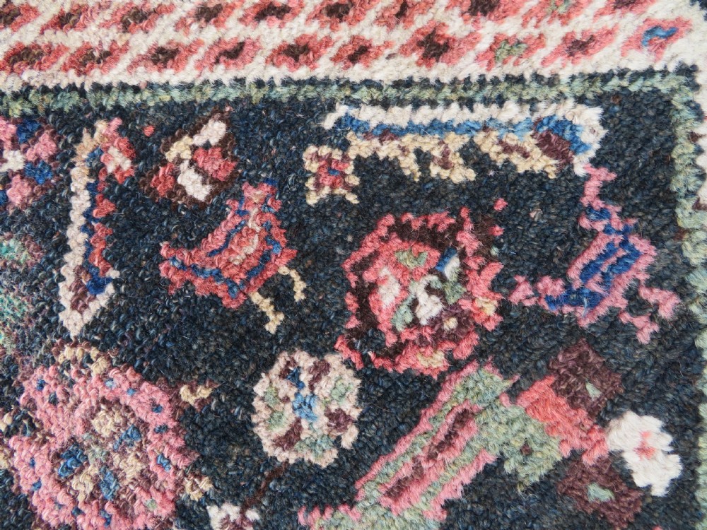 An antique Kurdish tribal rug featuring a cream field with stylized tree motifs, a central navy diamond medallion, and terracotta pink geometric borders. View IV