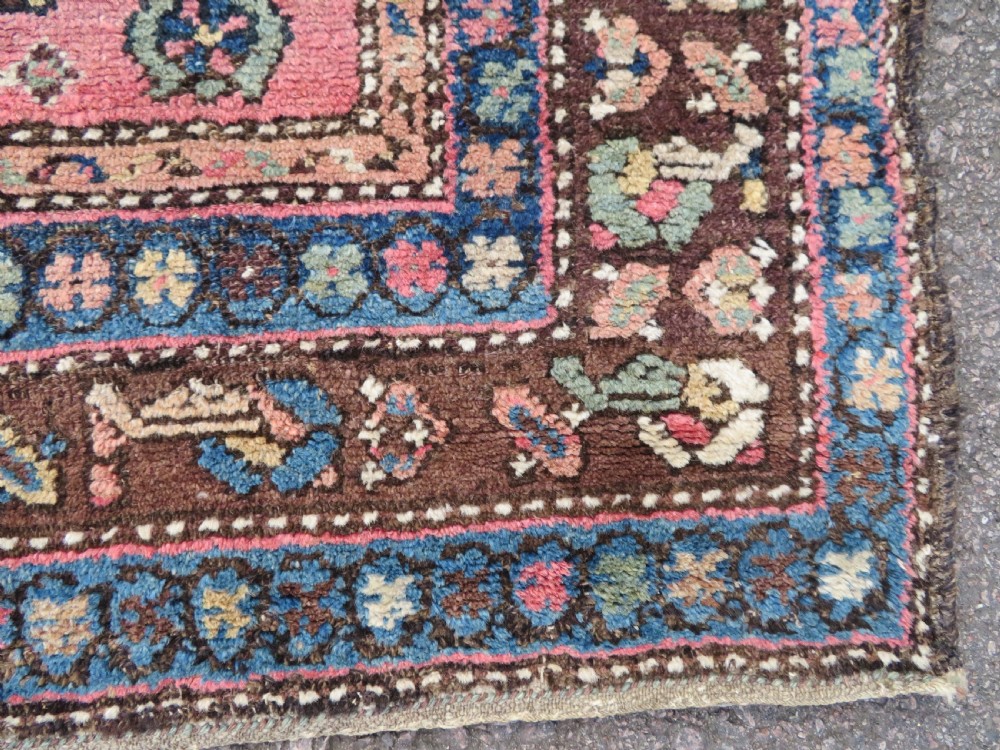 An antique Kurdish tribal rug featuring a cream field with stylized tree motifs, a central navy diamond medallion, and terracotta pink geometric borders. View VIII