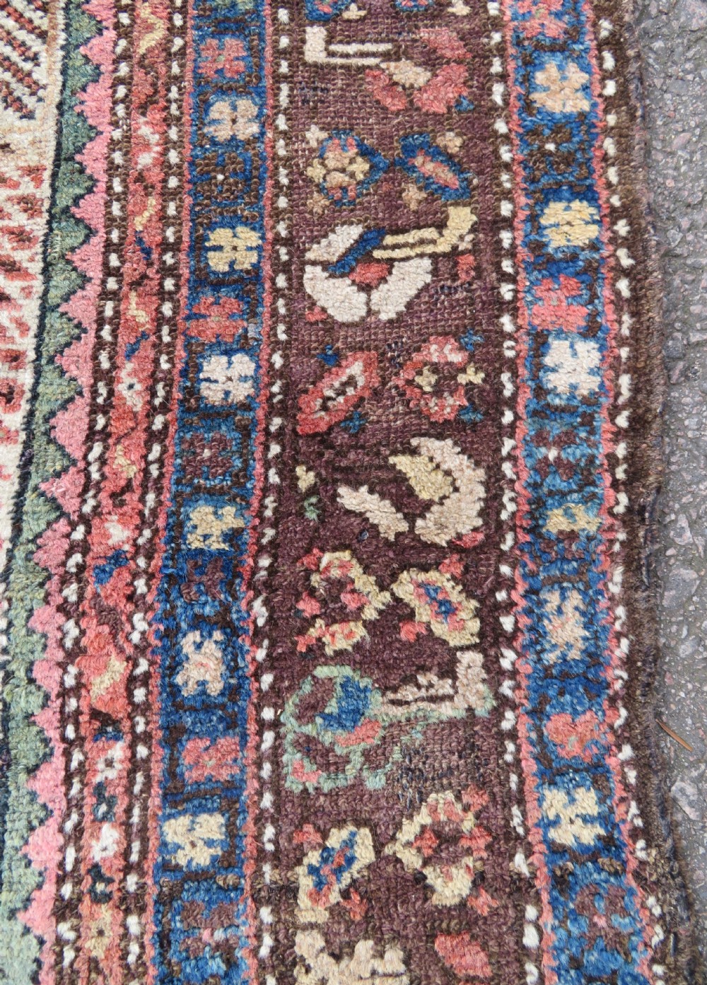 An antique Kurdish tribal rug featuring a cream field with stylized tree motifs, a central navy diamond medallion, and terracotta pink geometric borders. View IX