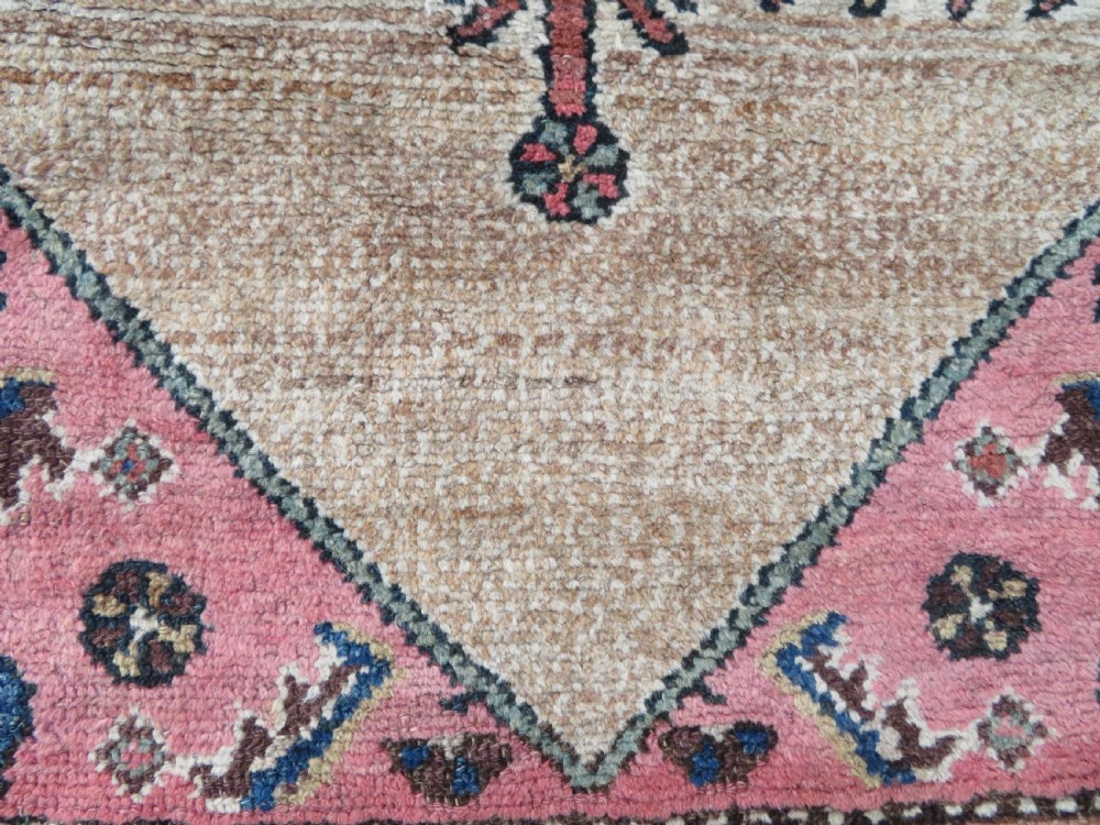 An antique Kurdish tribal rug featuring a cream field with stylized tree motifs, a central navy diamond medallion, and terracotta pink geometric borders. View XII