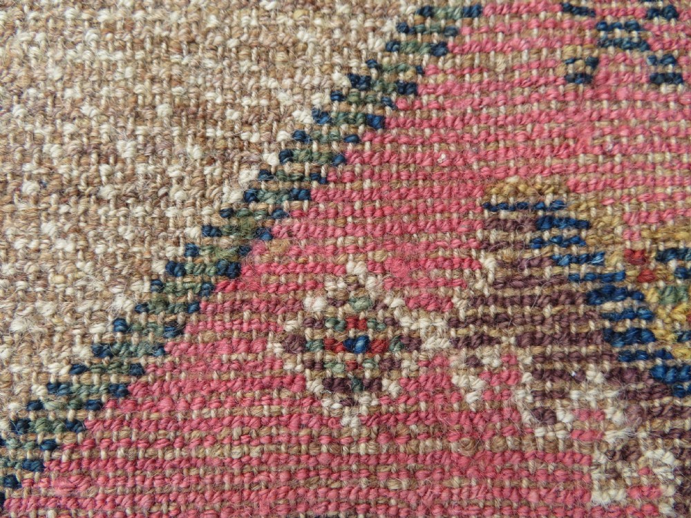 An antique Kurdish tribal rug featuring a cream field with stylized tree motifs, a central navy diamond medallion, and terracotta pink geometric borders. View XV