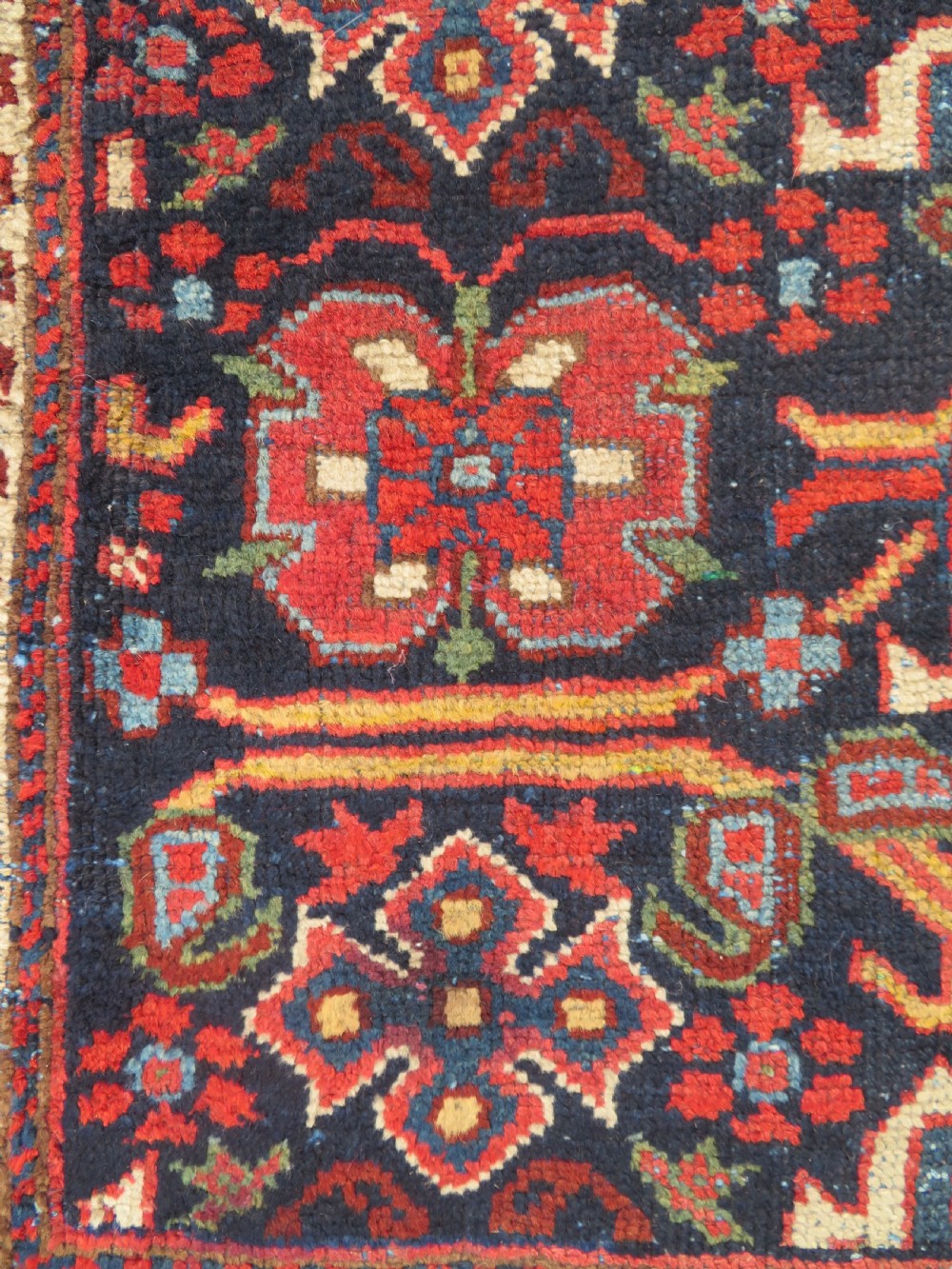 A rectangular hand-knotted antique Afshar rug featuring geometric floral motifs in terracotta red and sky blue on a deep navy blue background. View IV