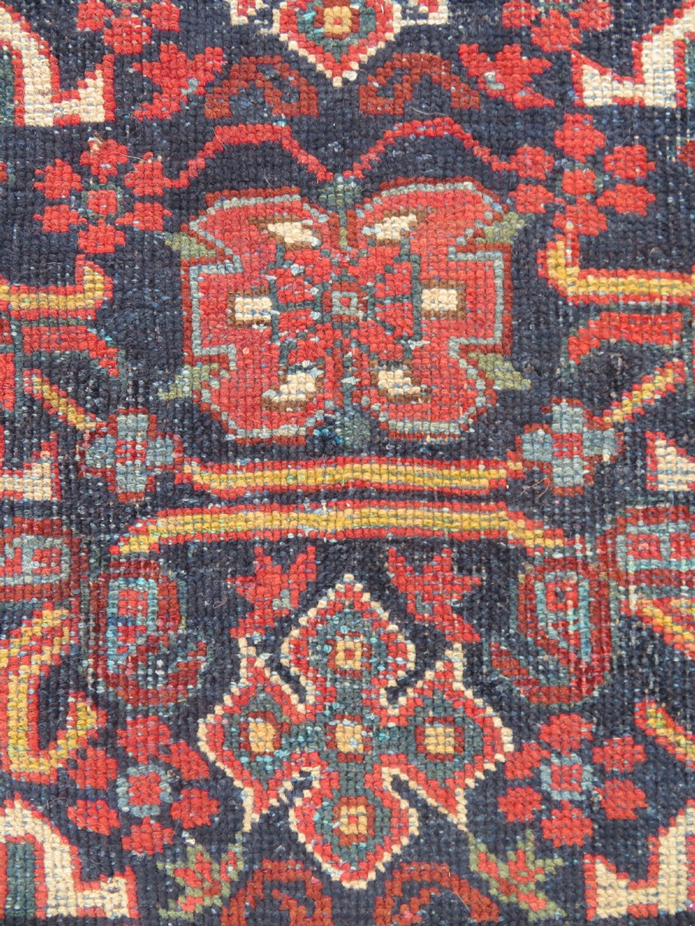 A rectangular hand-knotted antique Afshar rug featuring geometric floral motifs in terracotta red and sky blue on a deep navy blue background. View V