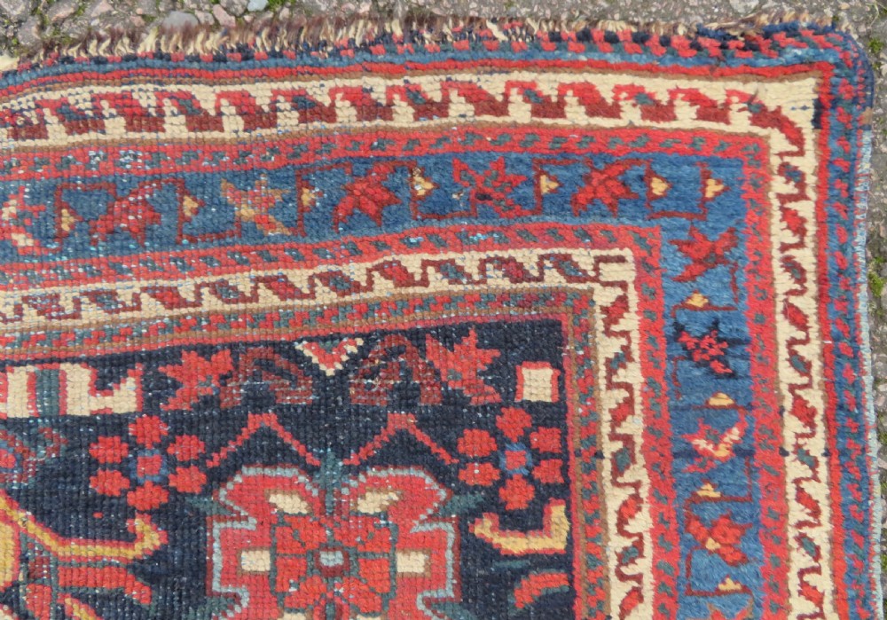A rectangular hand-knotted antique Afshar rug featuring geometric floral motifs in terracotta red and sky blue on a deep navy blue background. View VII