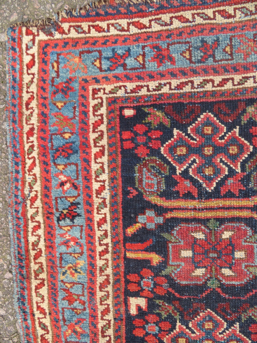 A rectangular hand-knotted antique Afshar rug featuring geometric floral motifs in terracotta red and sky blue on a deep navy blue background. View X