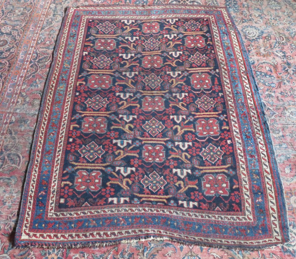 A rectangular hand-knotted antique Afshar rug featuring geometric floral motifs in terracotta red and sky blue on a deep navy blue background. View XV